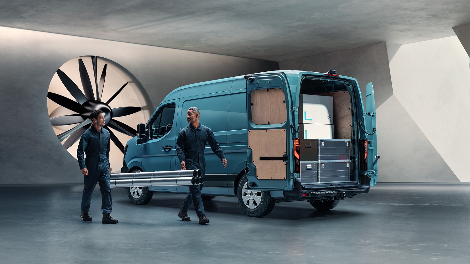 Pilkas Renault Master furgonas pastatytas priešais pastatą, šalia stovi vyras, laikantis santechniko įrangą