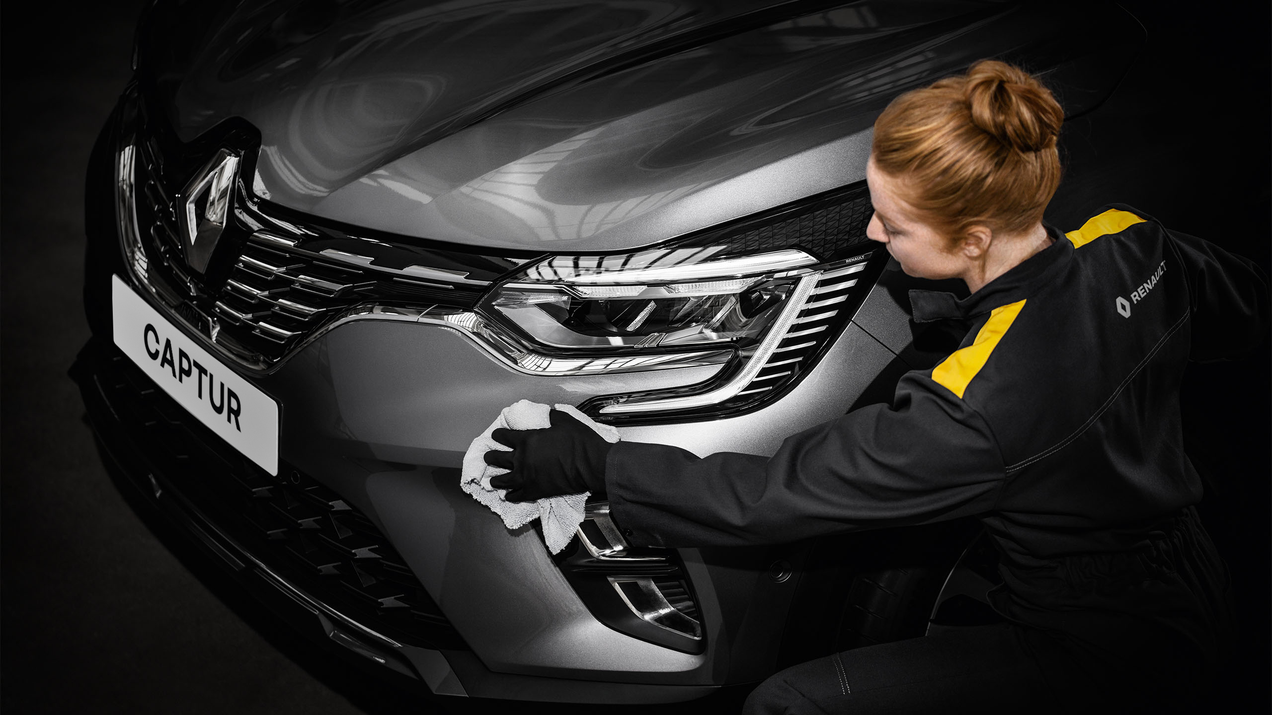 Serviso technikė kėbulo remonto dirbtuvėse šluoste valo pilko Renault automobilio priekinį buferį.