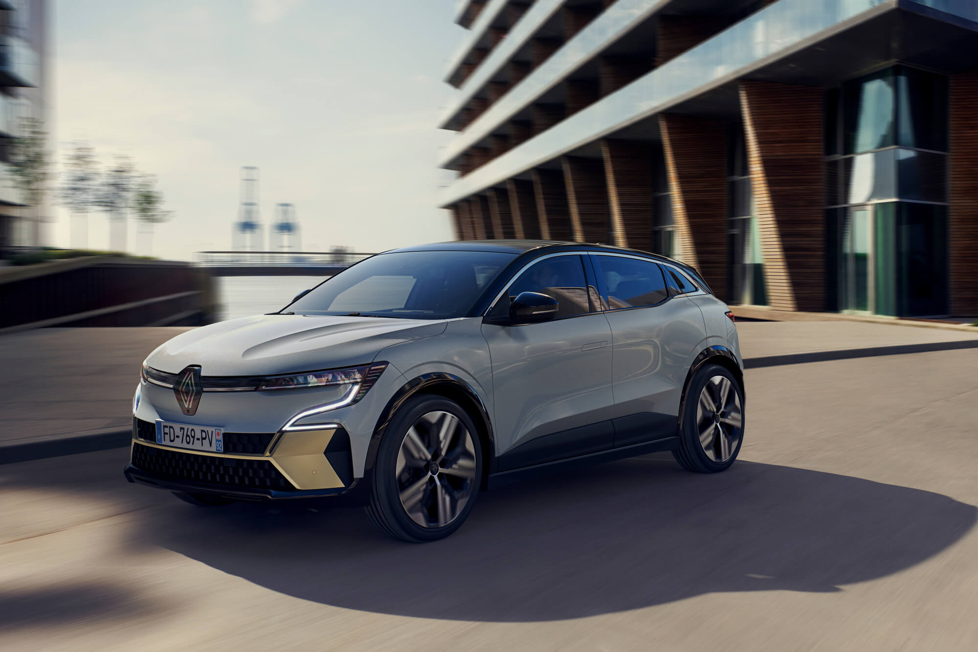 Pilkas visiškai elektrinis Renault MEGANE E-TECH Electric važiuoja gatve mieste