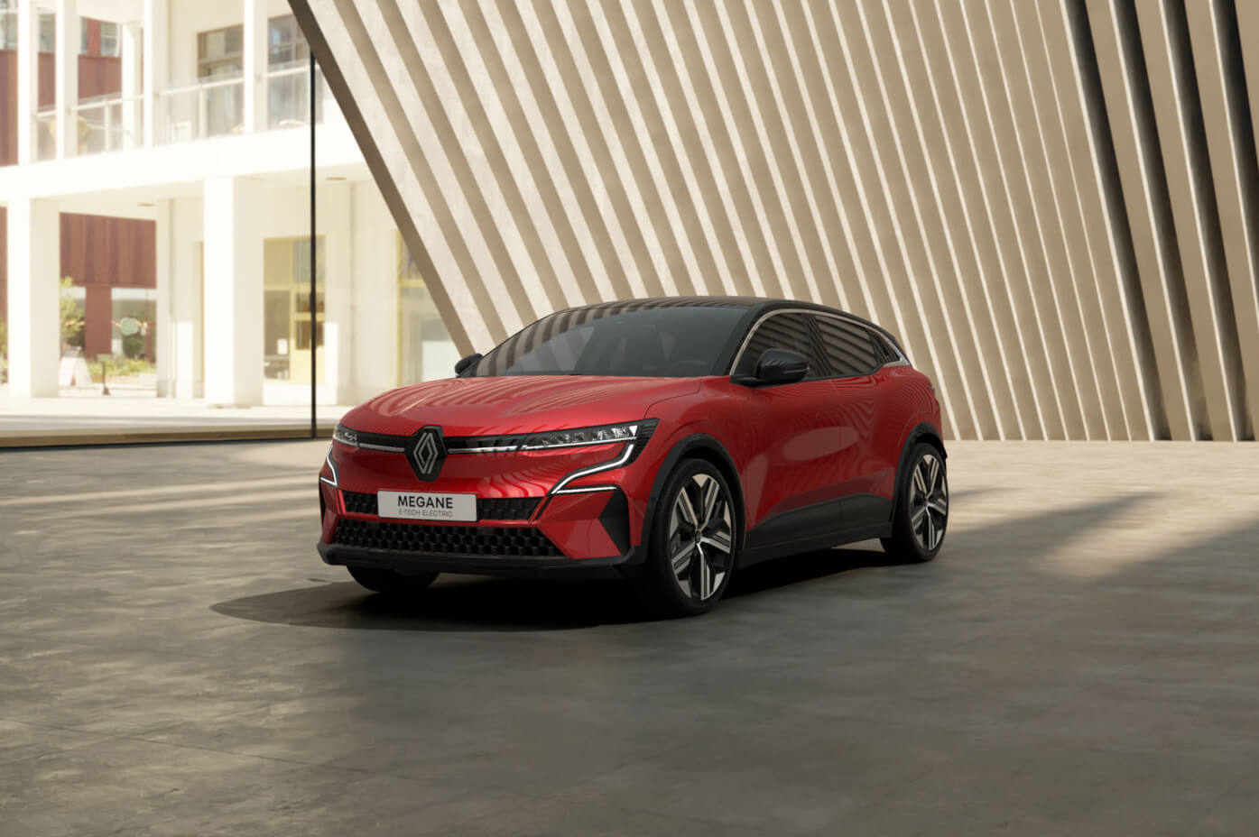 Raudono visiškai elektrinio Renault MEGANE E-TECH Electric vaizdas šonu iš priekio šviesioje studijos aplinkoje