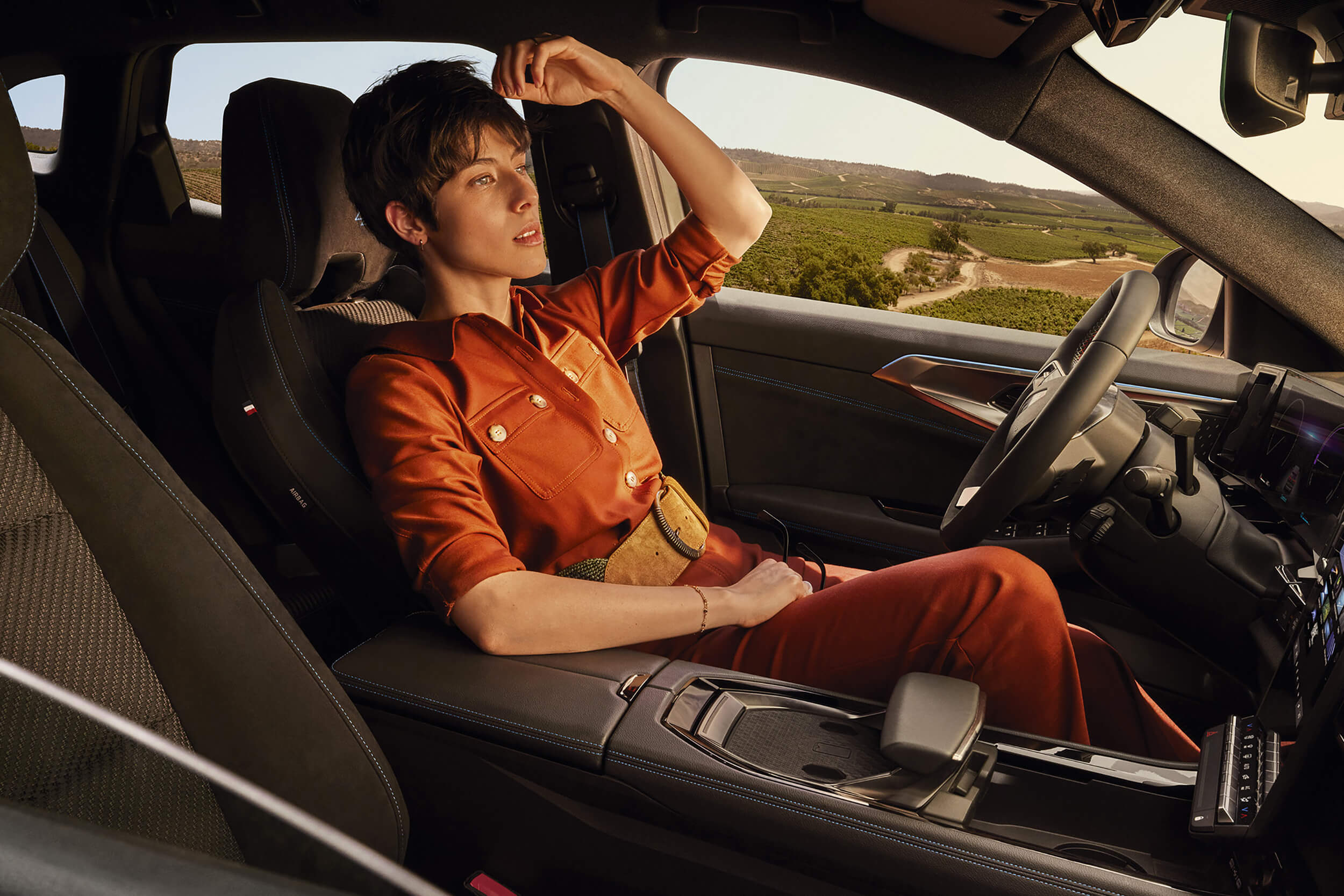 Moteris sėdi atsilošusi Renault Austral Esprit Alpine vairuotojo sėdynėje