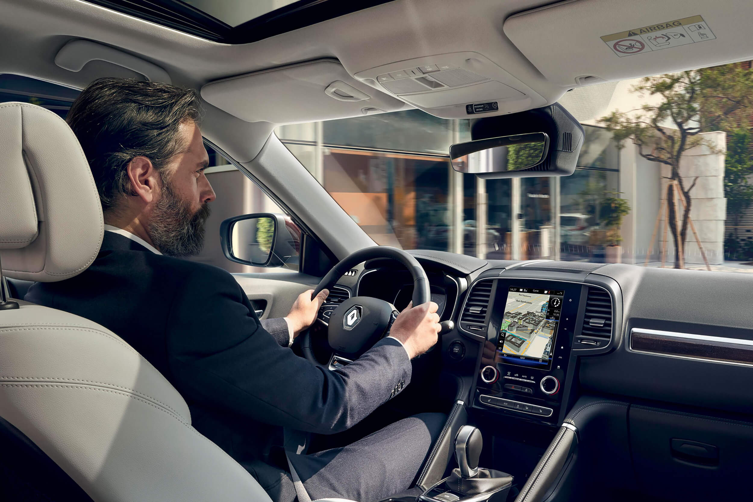 Vyras sėdi prie visureigio Renault Koleos vairo, matomas prietaisų skydas su centriniu ekranu